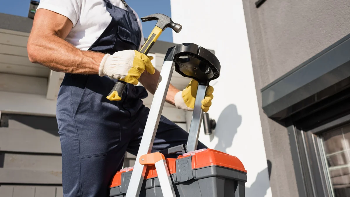 Handwerker mit Werkzeugkoffer auf einer Leiter
