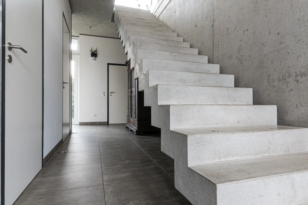 Moderner Eingangsbereich mit Sichtbeton und Design-Treppe – Immobilienmakler Siegburg präsentiert hochwertige Architektur im Innenraum