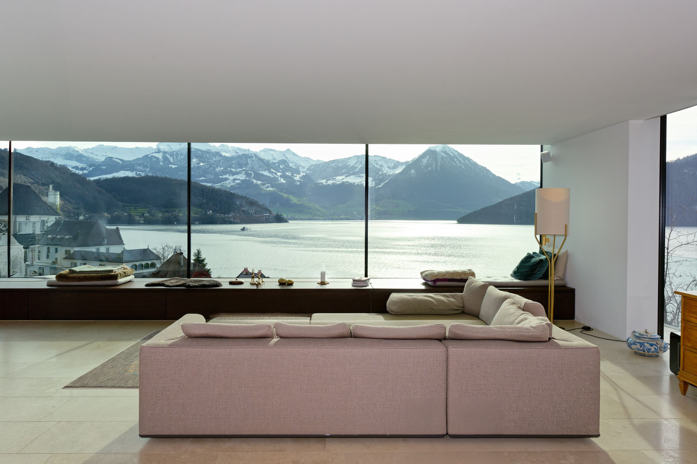 Wohnzimmer mit Panoramafenster und Blick auf See und Berge