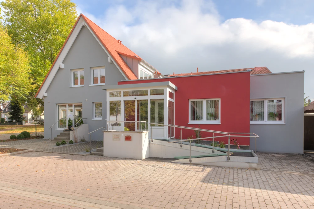 umbau-baeckerei-arztpraxis-31 Giebelhaus mit verglastem Windfang, rotem Anbau und barrierefreier Rampe mit Geländer