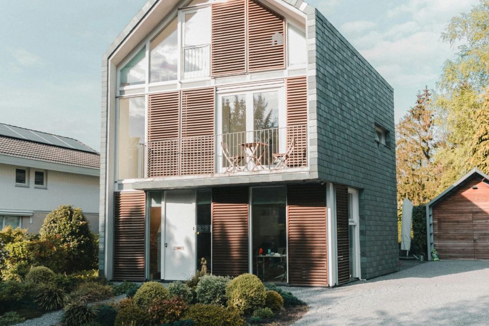 ernes Einfamilienhaus mit großer Glasfront, Holzverkleidung und gepflegtem Vorgarten bei Tageslicht