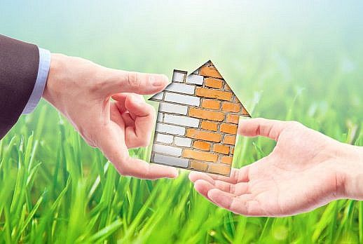 Ein grafisch dargestelltes Haus wird von einem  Immobilienmakler aus Kassel/Hessen an den Mieter übergeben.