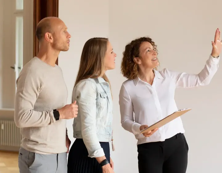 Junges Paar mit Immobilienmaklerin bei Besichtigung