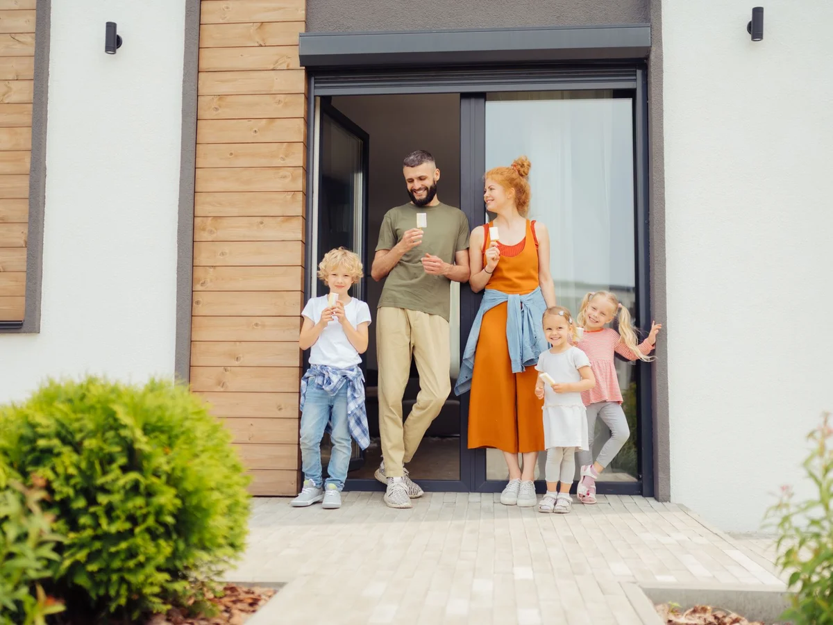 Familie mit Kindern vor der Haustür eines Einfamilienhauses